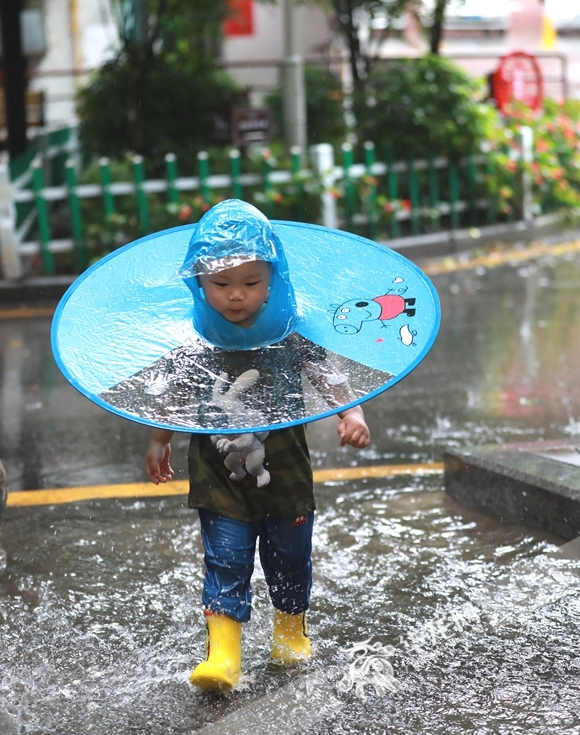 小孩子跑过积水路段。华龙网-新重庆客户端首席记者 李文科 摄 916462829654401479